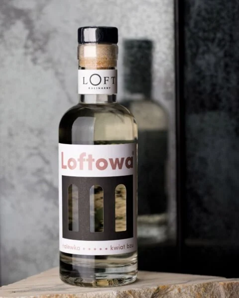 Nalewka z kwiatu bzu w butelce 350 ml o jasnożółtej barwie na loftowym tle