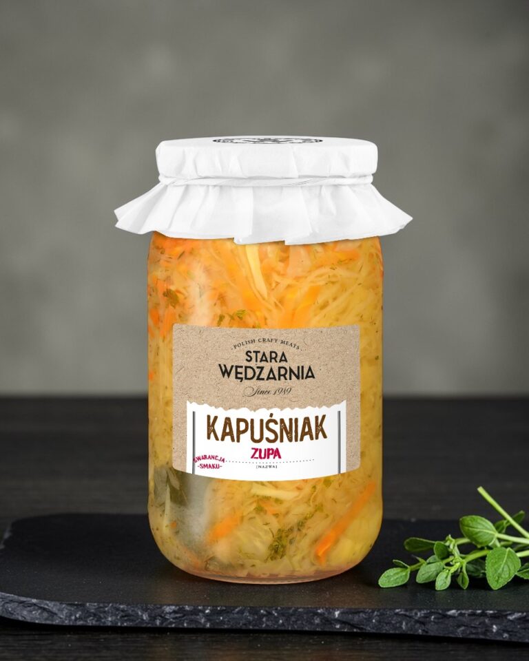 Kapuśniak Stara Wędzarnia - na czarnym kamiennym talerzu, drewniany stol, szare cementowe tlo, zielone ziola