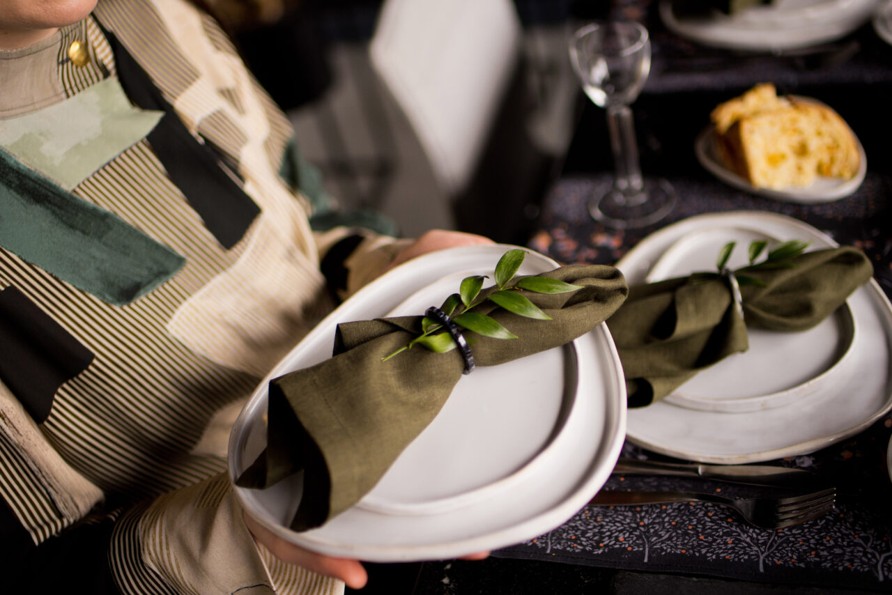 Loftowy stół na Wielkanoc - biały len, czarne dodatki, gałązki zieleni i jaja ułożone na czarnej paterze