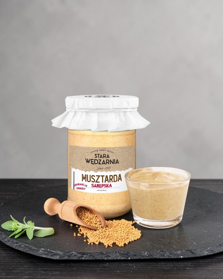 Musztarda sarepska Stara Wędzarnia - na czarnym kamiennym talerzu, drewniany stol, szare cementowe tlo, zielone ziola