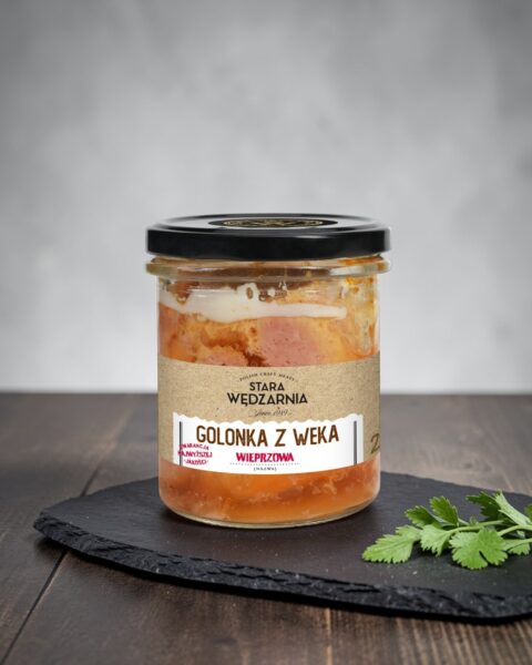 Golonka z weka Stara Wędzarnia - na czarnym kamiennym talerzu, drewniany stol, szare cementowe tlo, zielone ziola