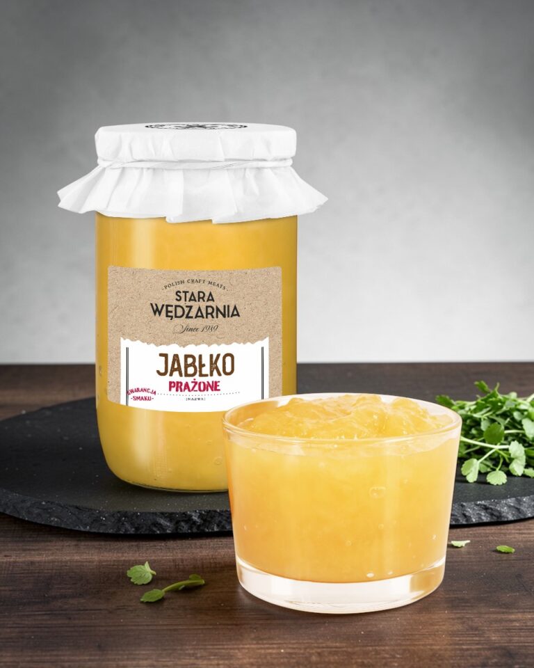 Jabłko prażone Stara Wędzarnia - na czarnym kamiennym talerzu, drewniany stol, szare cementowe tlo, zielone ziola