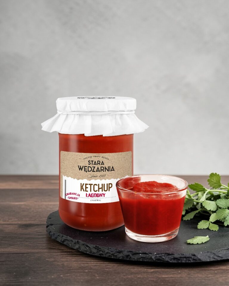 Ketchup łagodny Stara Wędzarnia - na czarnym kamiennym talerzu, drewniany stol, szare cementowe tlo, zielone ziola