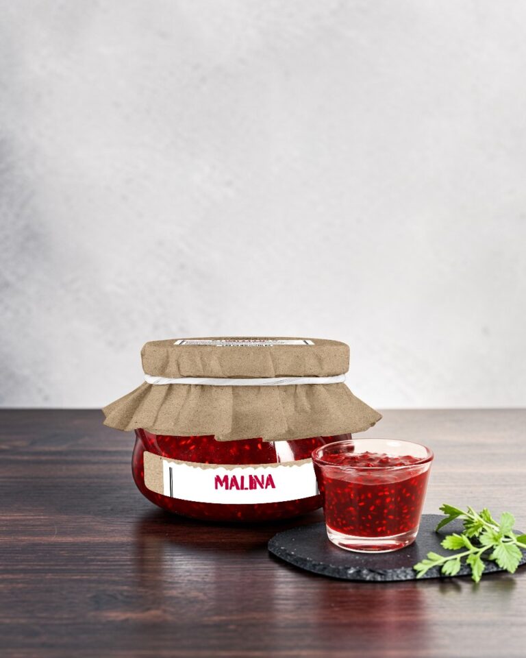 Konfitura malinowa Stara Wędzarnia - na czarnym kamiennym talerzu, drewniany stol, szare cementowe tlo, zielone ziola