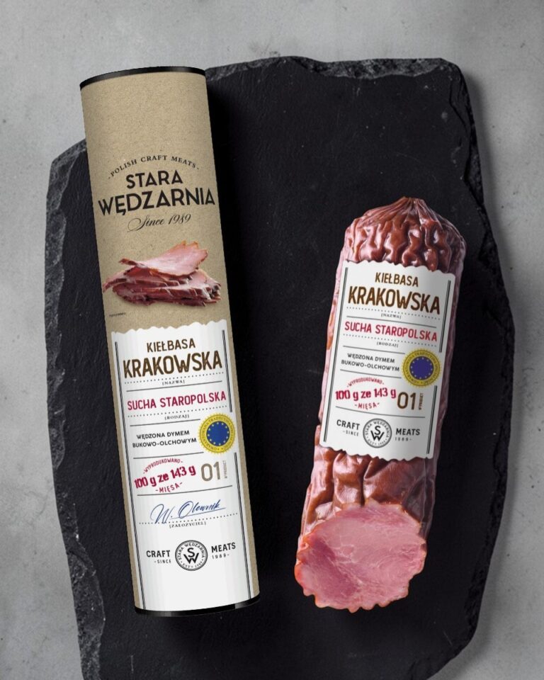 Krakowska sucha GTS w tubie Stara Wędzarnia - na czarnym kamiennym talerzu, drewniany stol, szare cementowe tlo, zielone ziola