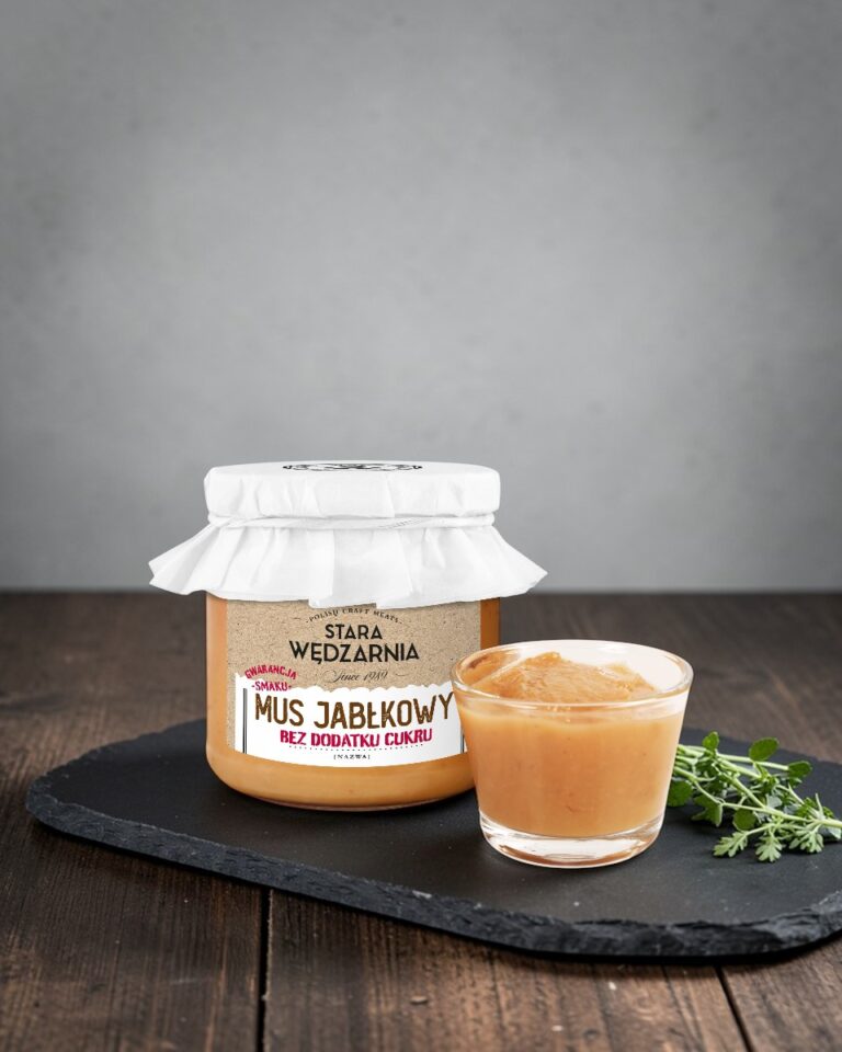 Mus jabłkowy bez dodatku cukru Stara Wędzarnia - na czarnym kamiennym talerzu, drewniany stol, szare cementowe tlo, zielone ziola