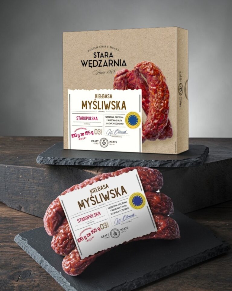 Myśliwska Staropolska GTS pudełko Stara Wędzarnia - na czarnym kamiennym talerzu, drewniany stol, szare cementowe tlo, zielone ziola