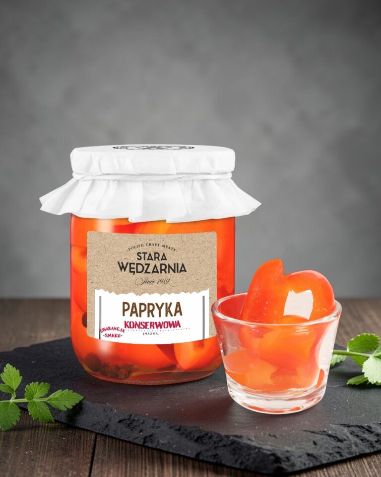 Papryka konserwowa Stara Wędzarnia - na czarnym kamiennym talerzu, drewniany stol, szare cementowe tlo, zielone ziola