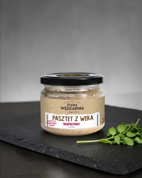 Pasztet z weka wieprzowy Stara Wędzarnia - na czarnym kamiennym talerzu, drewniany stol, szare cementowe tlo, zielone ziola