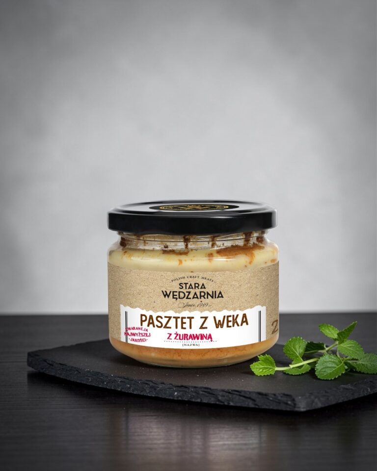 Pasztet z weka z żurawiną Stara Wędzarnia - na czarnym kamiennym talerzu, drewniany stol, szare cementowe tlo, zielone ziola