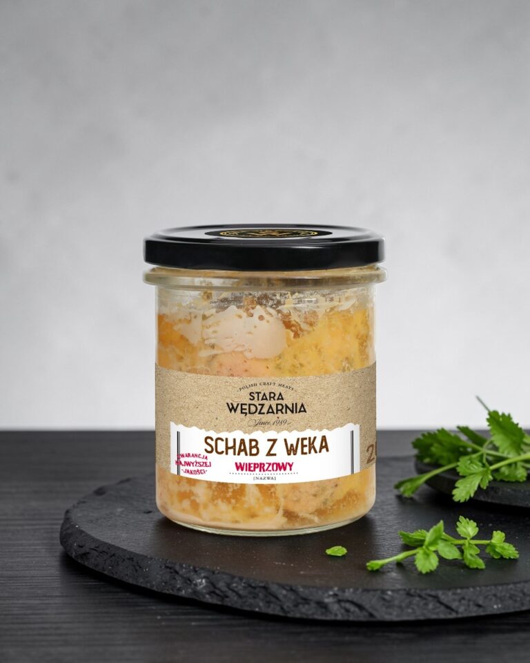 Schab z weka wieprzowy Stara Wędzarnia - na czarnym kamiennym talerzu, drewniany stol, szare cementowe tlo, zielone ziola